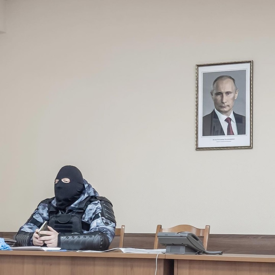 La celebre fotografia di Dmitry Markov, il fotografo russo che scattò l'immagine dell'agente antisommossa con il ritratto di Putin alle sue spalle